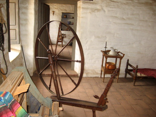 A spinning wheel in one of the simple rooms suggests what life was like.