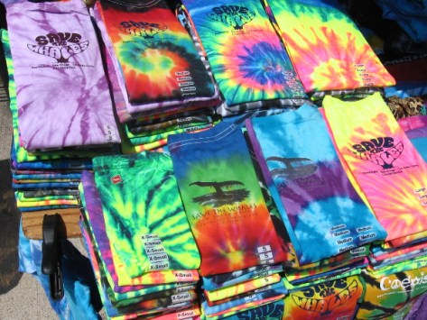 Bright piles of tie-dye shirts for sale on Embarcadero sidewalk.