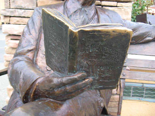 Mark Twain is reading his own classic American novel Adventures of Huckleberry Finn.