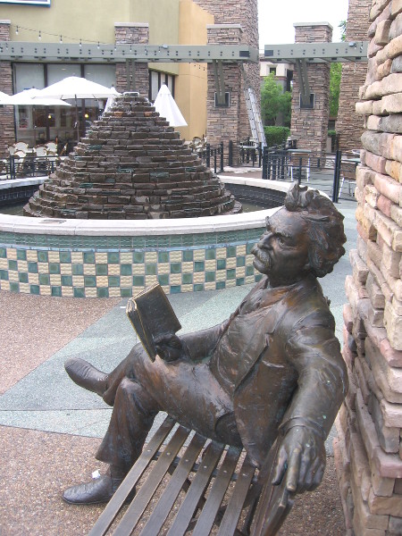 Famous author sits on bench by fountain in front of IHOP.