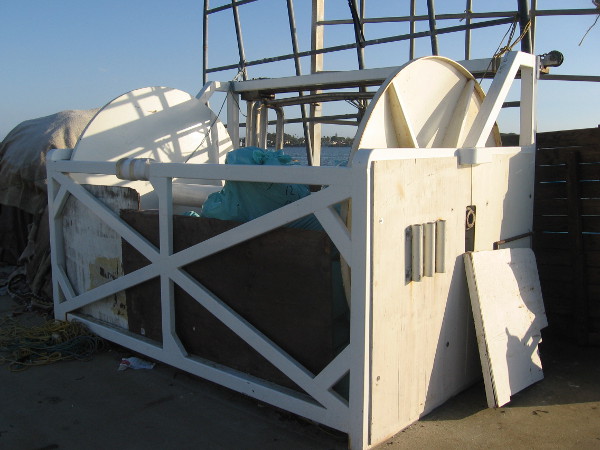 Huge cylinder used by live bait boats to haul in nets glows with reflected sunlight.