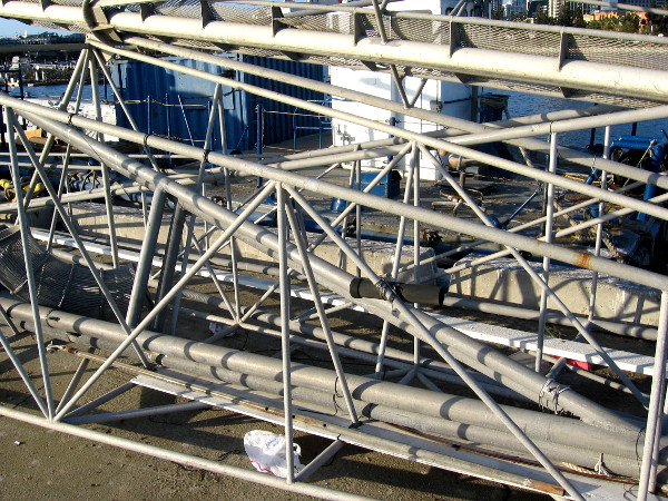 Crazy ship's structure on pier almost conceals docked fishing vessel.