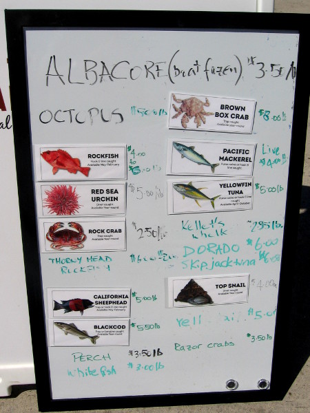 Sign board at foot of pier indicates today's prices.