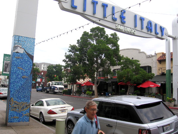 Pedestrian passes Little Italy sign on India Street in San Diego.