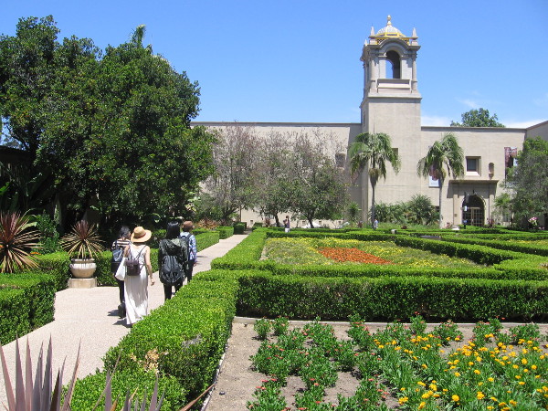 Visitors walk through Balboa Park's Alcazar Garden on a summer day.