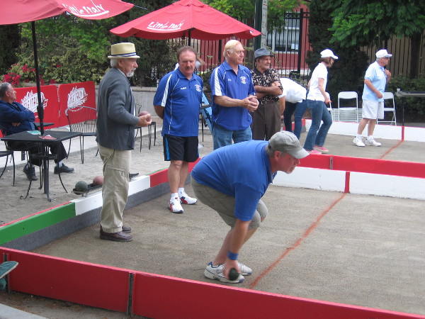 Man prepares to strategically send bocce ball down the long court.