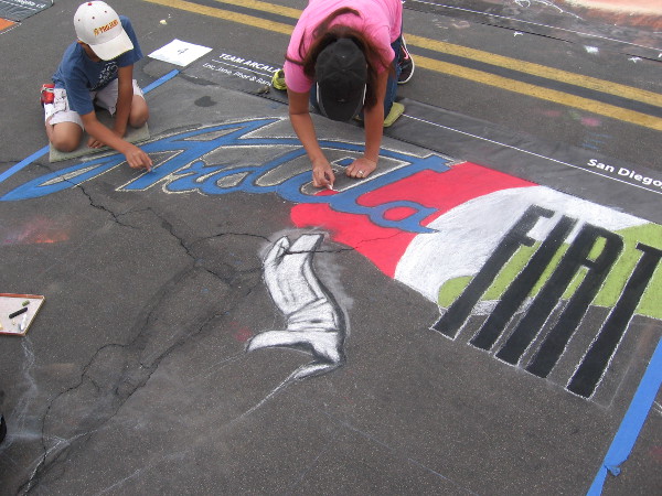 Team Arcala creating some chalk art that includes the Fiat logo.