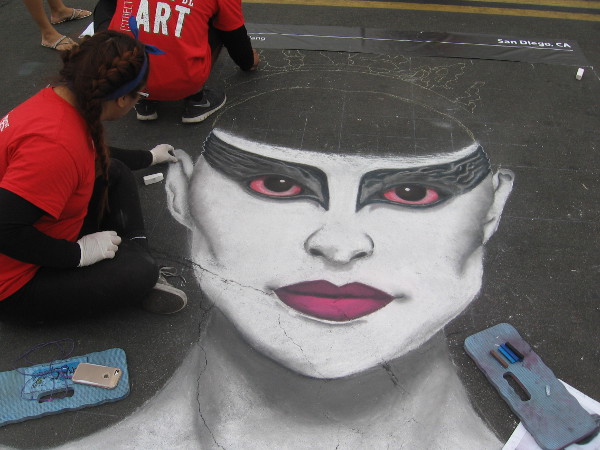 Megnificent is bringing a bold face into existence using chalk.