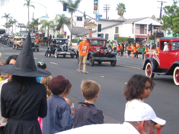 Here comes a long line of classic cars with spooky decorations.