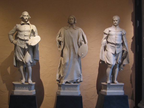 Plaster statues of Spanish painters become shadowy in courtyard of Casa del Prado.