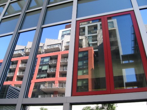 Reflection in west side windows shows colorful building across the street.