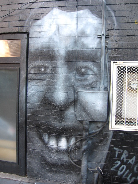 Smiling face painted on building wall on 16th Street in East Village.