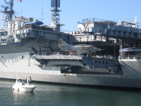 Small boat passes near USS Midway aircraft carrier on San Diego Bay.