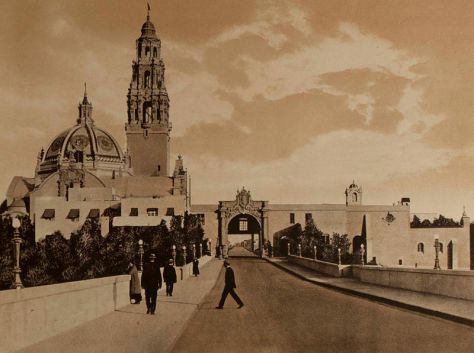 Photograph of the Panama-California Exposition's La Puerta del Oeste (west entrance) taken from Cabrillo Bridge. Dome and bell tower of the California State Building rise into the San Diego sky.