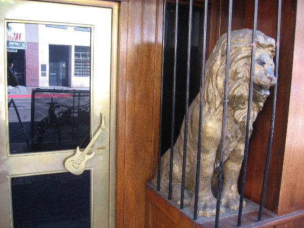 Caged lion in the Gaslamp guards the Hard Rock Cafe, and a door with electric guitar handle.