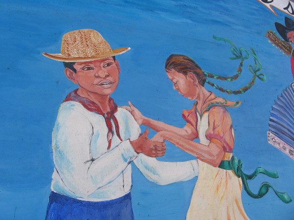 Young man and lady dance on the festive outdoor mural.