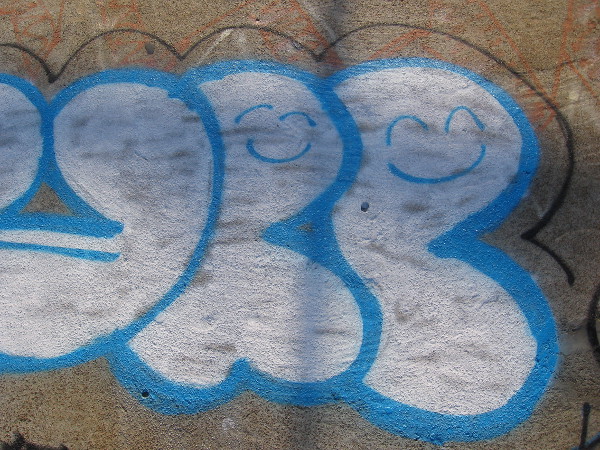 Two contented smiles inside lettering of boldly spray painted graffiti underfoot.