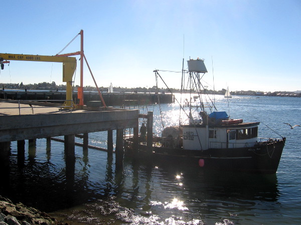 Fishing boat passes by the dock and crane.