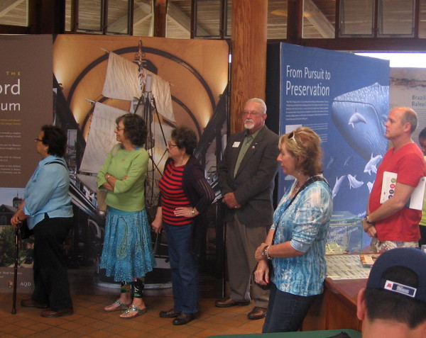 People listen to presentation at opening of Yankee Baleeiros whaling exhibit.