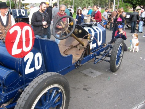 A large crowd enjoys many super cool cars in front of San Diego Automotive Museum.