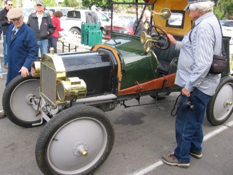 One guy checks out the steering wheel, another the unusual wheels on the asphalt!