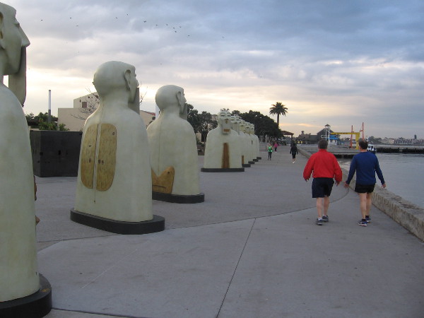 People walk past provocative public art as day dawns near Seaport Village.