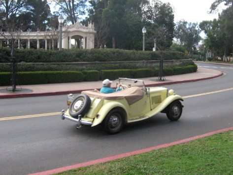 Guy drives his classic automobile through Balboa Park, heading to a special car show.