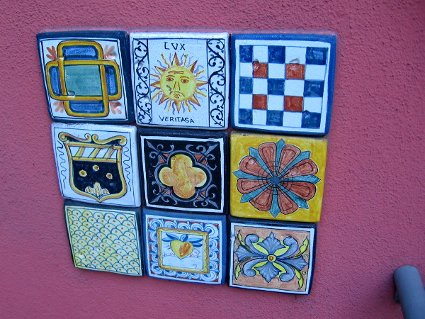 Painted tiles add zest to a wall by a sidewalk.