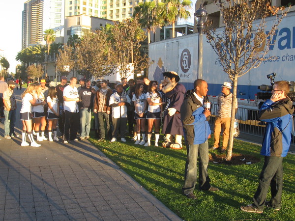 Television news people, the Pad Squad and fans watch Padres begin move to Spring Training.