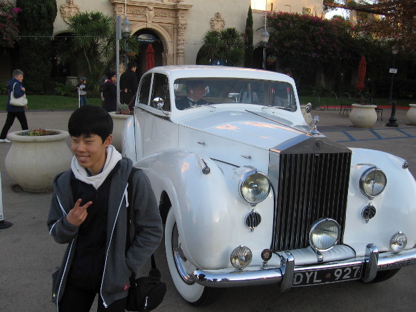 Someone poses for a photo by Rolls Royce limo standing by in Balboa Park.