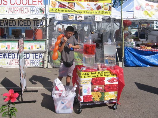 Young man selling treats pumps up a balloon.