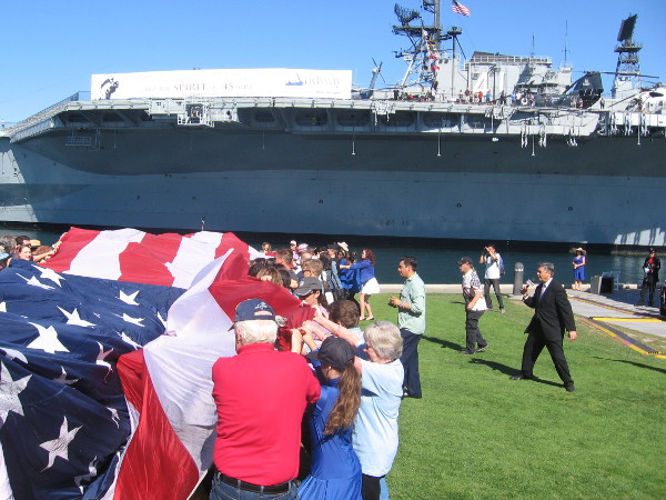 The giant billowing flag is unfurled by everyday citizens proud and happy to be free.