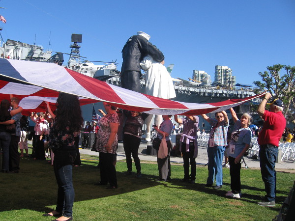 People carefully hold up the American flag in a tribute to fallen heroes.
