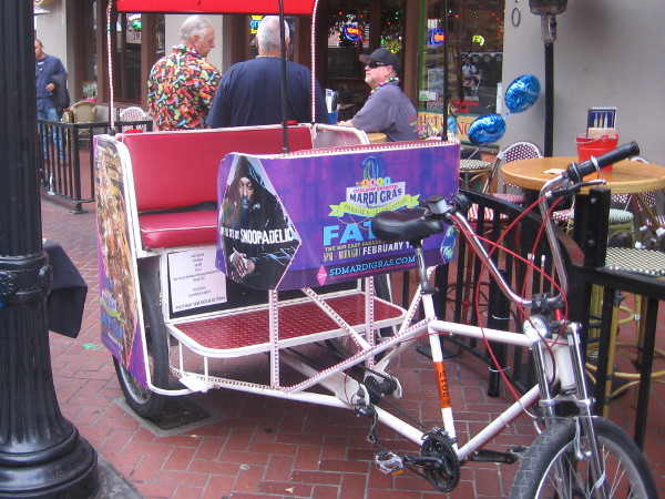 This pedicab is covered with Fat Tuesday ads and flashing lights.