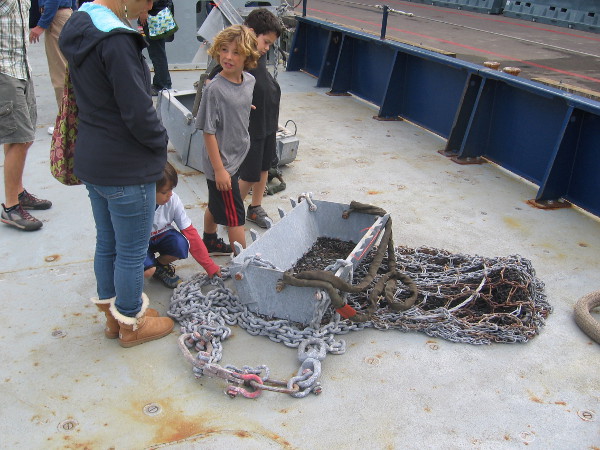 Kids examine a rock dredge, used for the recovery of heavy material on the ocean floor.