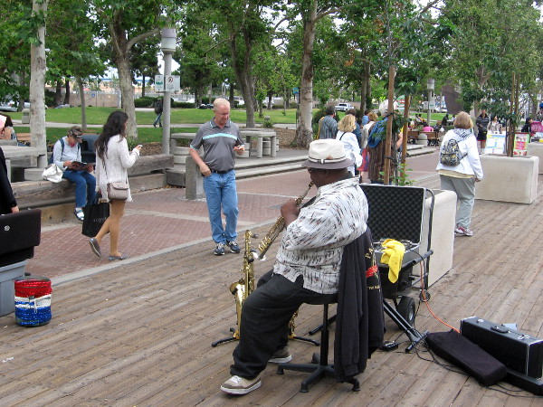 People staring downward and street musician near USS Midway.