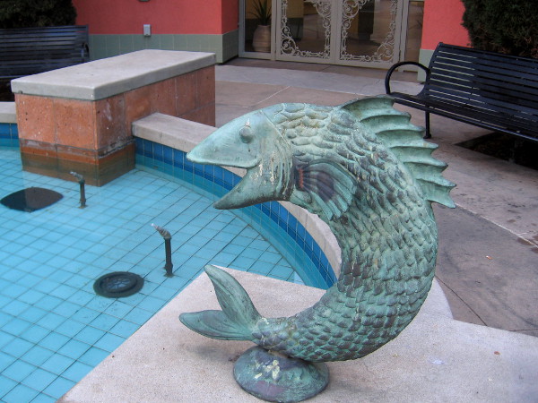 Metal fish sculpture seems to leap from Piazza Villaggio fountain.