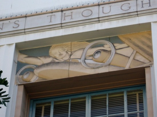 Art Deco relief work shows female above propellers of airplane.