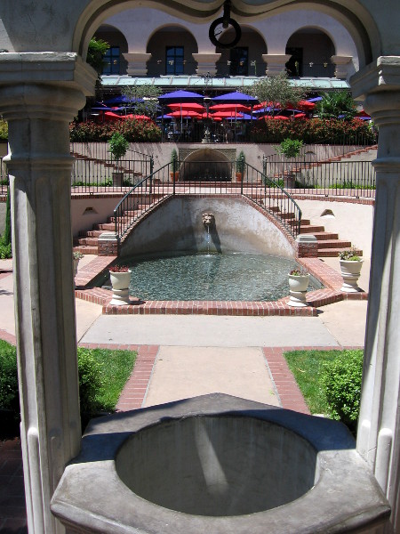 A wishing well frames two elegant, classic fountains.
