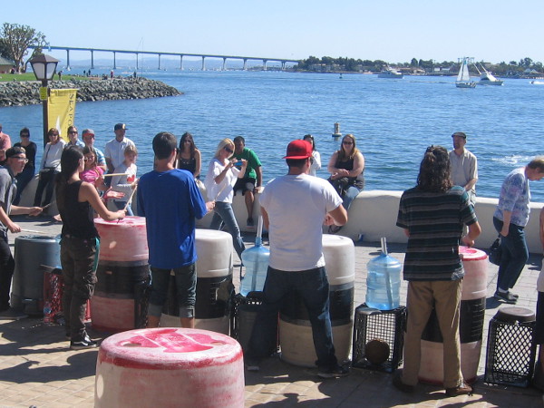 Unusual instruments produce fun beats as busker festival visitors sit in sunshine by San Diego Bay.