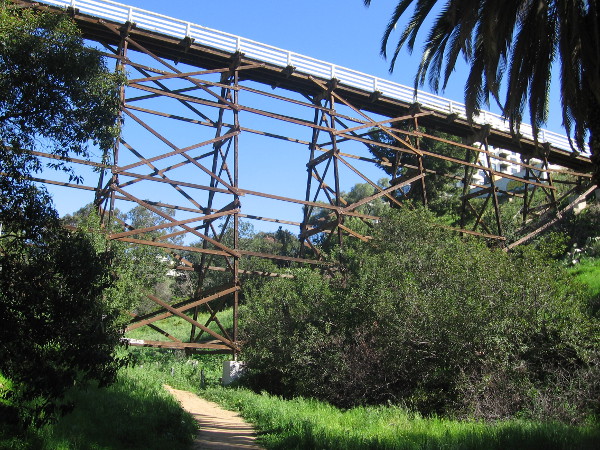 Looking up at the wooden footbridge from the quiet footpath on a sunny day.