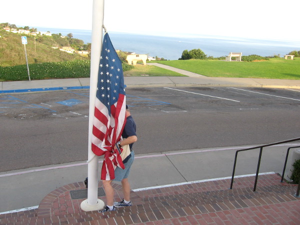 The Stars and Stripes is carefully attached, ready to be lifted into the wide, blue sky.