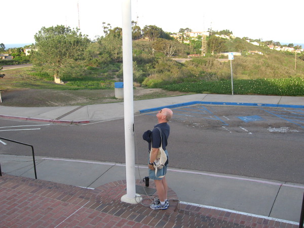 The volunteer momentarily lowered the flag to half-mast, to honor the fallen. He then raised it to the top and showed his respect.