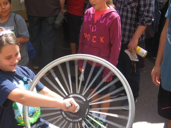 Girl learns about gyroscopes and angular momentum with a spinning bicycle tire.