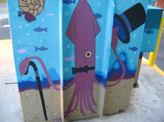 Squid with top hat and cane entertains passersby on a Hillcrest utility box.