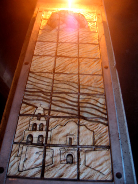 Human brain, made golden by underpass light, crowns image of Mission San Diego de Alcalá and the ever-present river.