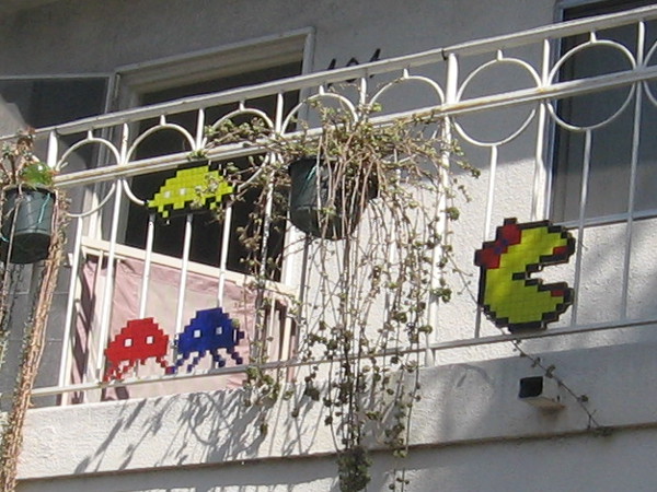 Ms. Pacman, Space Invaders and other video game legends hang out on a porch railing.