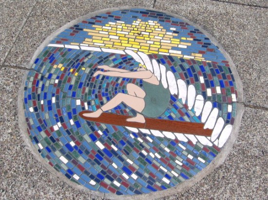 Surfer rides an eternal wave under the feet of passing pedestrians.