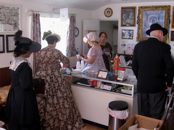 People in period costumes enjoy some treats inside the small cottage.