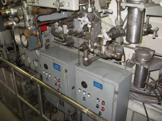 High-Pressure Air Compressor Controllers among a jumble of pipes and valves.